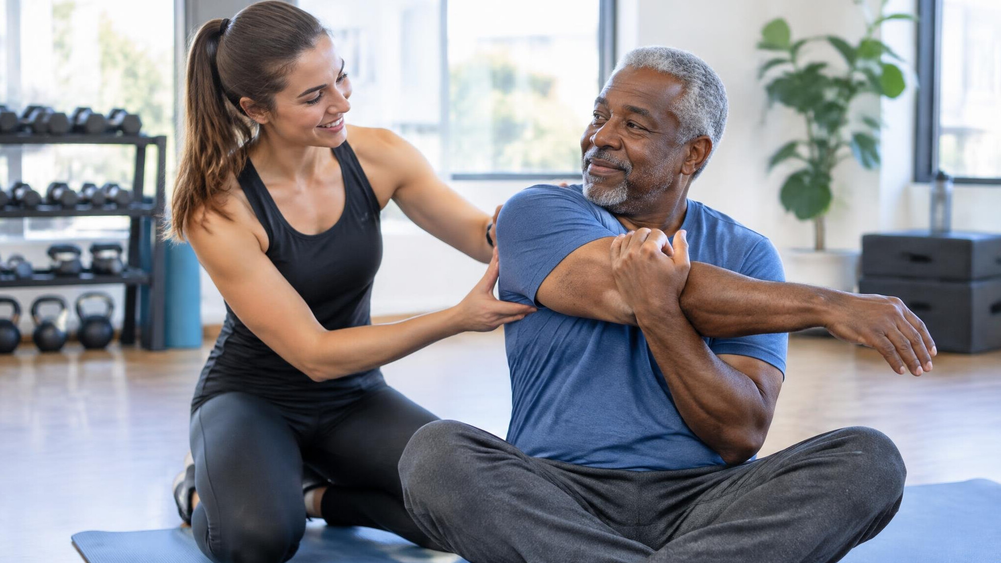 Instructor helping an older adult with a stretching exercise